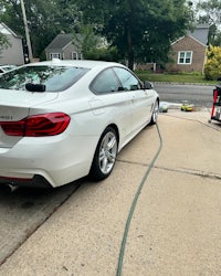 a white bmw 4 series being cleaned by a hose