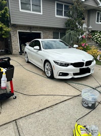 a white car is being washed in front of a house