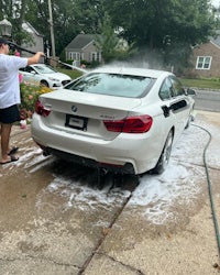 a man washing a white car with a hose