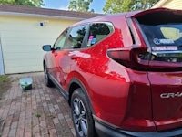 a red honda cr - v is parked in front of a house